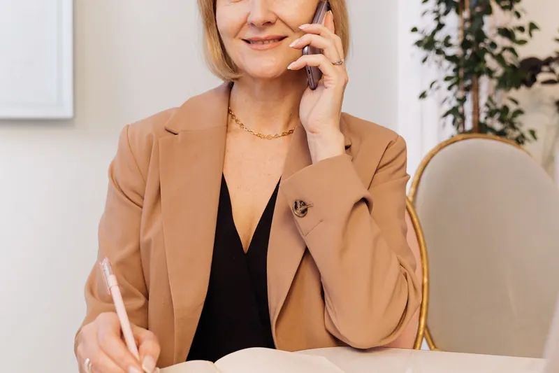 A woman taking notes during a phone call at home
